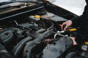 Close-up of a mechanic's hands working on a car engine, showcasing repair work.