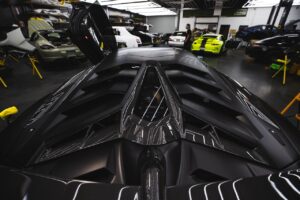 Detailed view of a sports car with a carbon fiber roof in a professional auto repair shop.